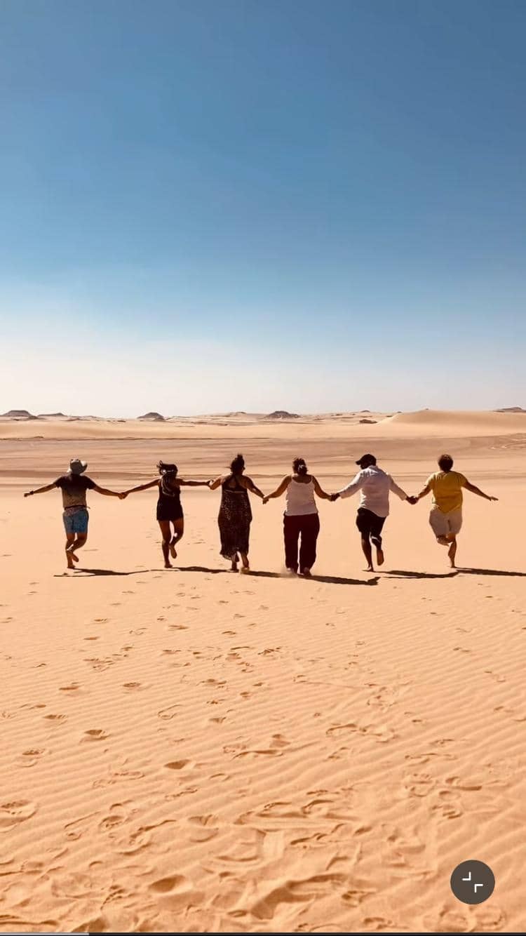 Grupo de viajeros tomados de la mano en el desierto egipcio